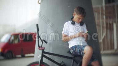 男孩坐在BMX自行<strong>车上</strong>，听智能手机上的<strong>音乐</strong>